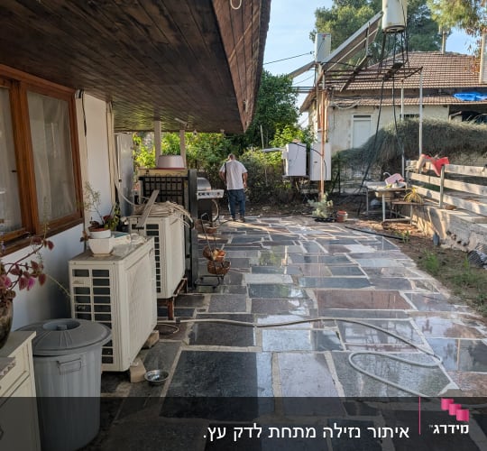 אדם עובד בחצר עם ציוד טכני ומיכלים